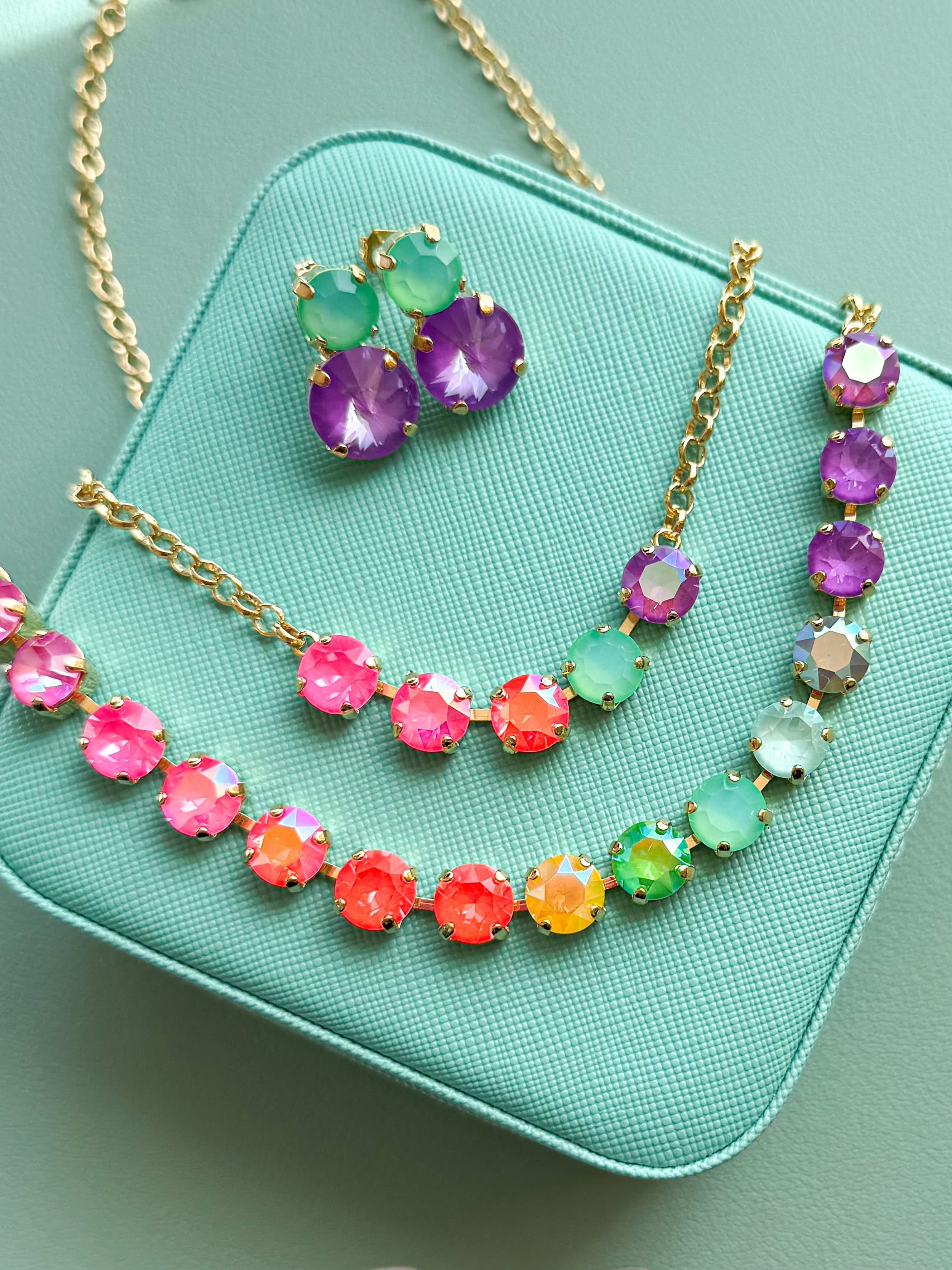 Colorful Swarovski crystal necklaces and stud earrings on a teal jewelry box